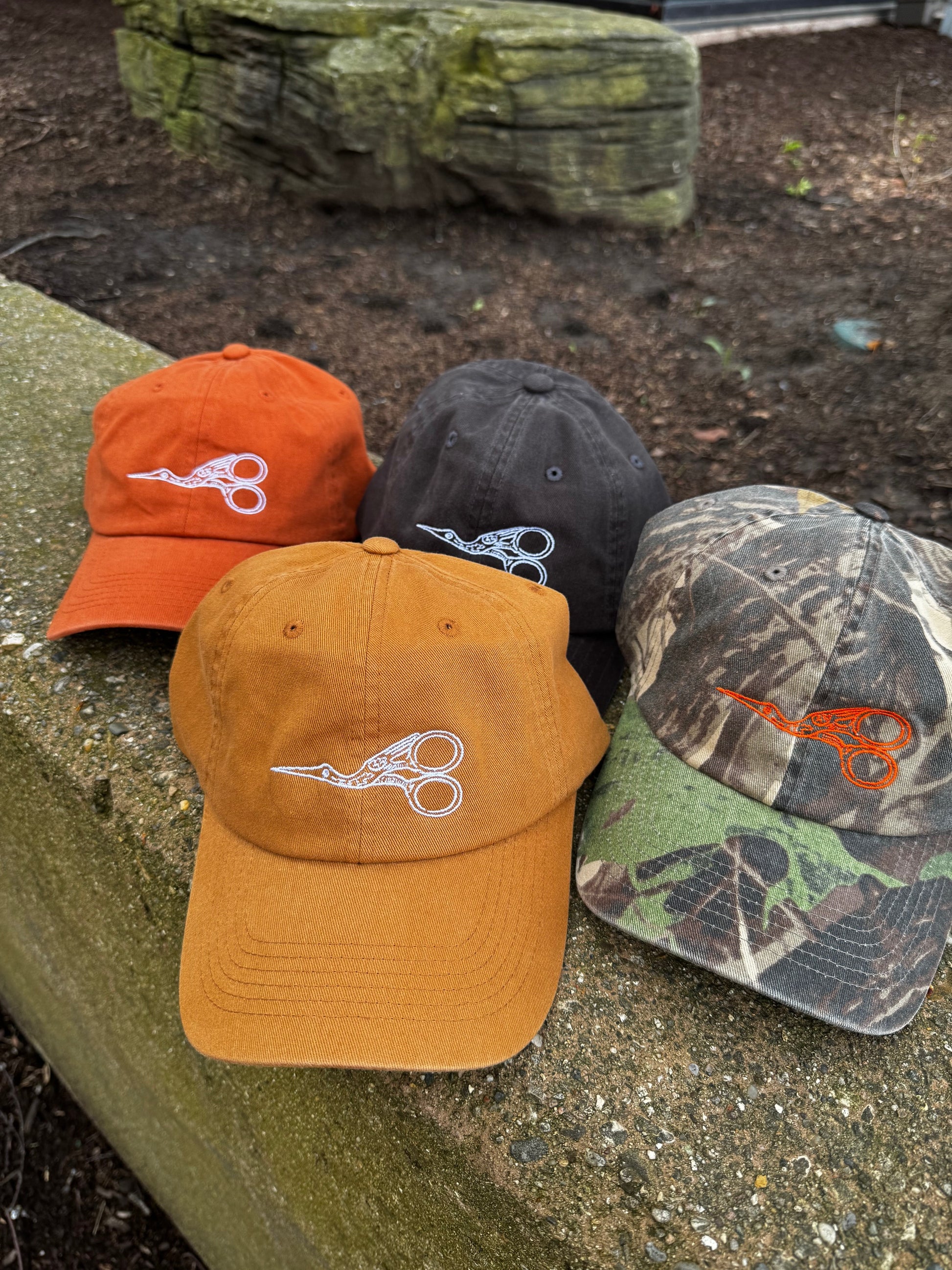 Four baseball caps with the same design on a stone surface